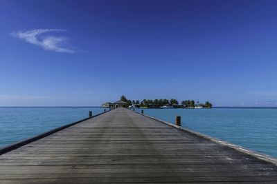 Pier over sea against blue sky