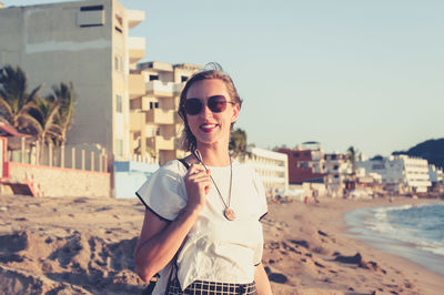 Young woman smiling at the beach at sunset