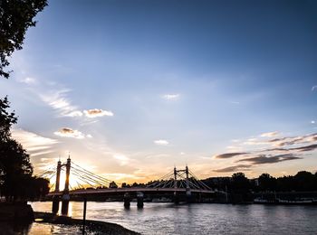 Bridge over river against cloudy sky