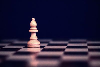 Close-up of bishop on chess board against black background