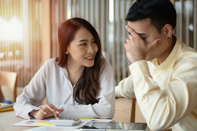 Young couple looking down while sitting on table