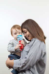 Full length of mother and daughter against white background