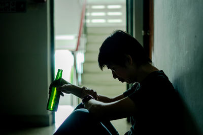 Side view of woman looking through window at home