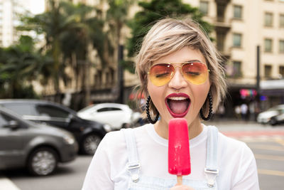 Beautiful young woman having flavored ice on city street