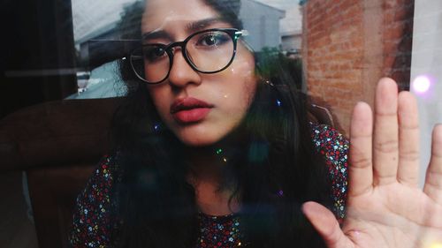 Portrait of beautiful young woman seen through glass window