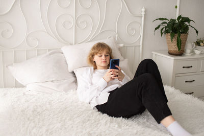 Young woman sitting on bed at home