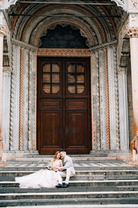 Woman leaning on staircase of building