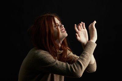 Portrait of woman wearing hat against black background