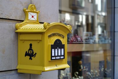 Close-up of yellow mailbox on wall