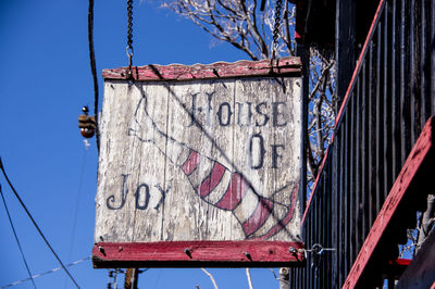 Low angle view of sign against blue sky