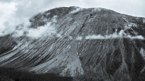 A black and white photo of a rough rocky mountain and fog, banff, canada.