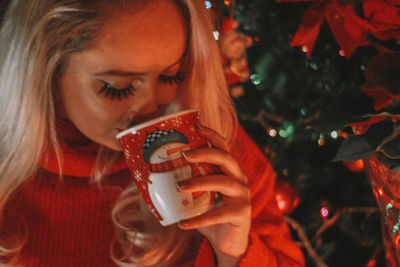 Midsection of woman holding drink with christmas tree