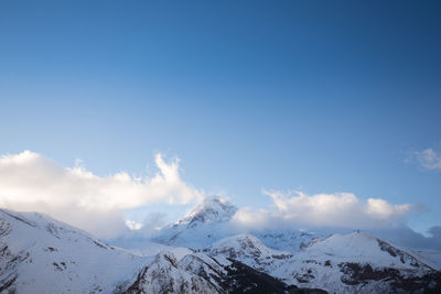 Scenic view of snowcapped mountains against blue sky