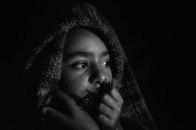 Portrait of girl looking away against black background