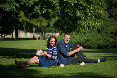 Man with woman sitting on grassy field at park