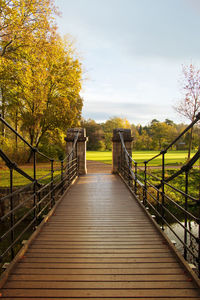 Footbridge amidst plants and trees against sky