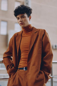 Portrait of young woman standing against wall