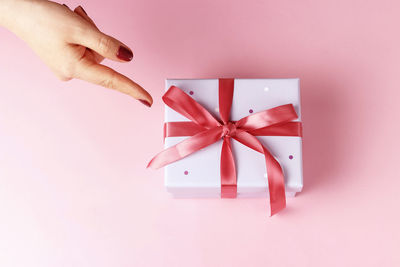 Close-up of hand holding red box against white background