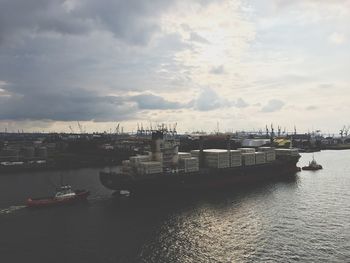 Boats in harbor against sky in city