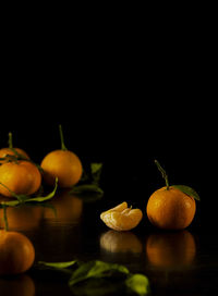 Still life of mandarins and leaves against black background