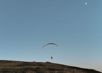 Low angle view of person paragliding against clear sky