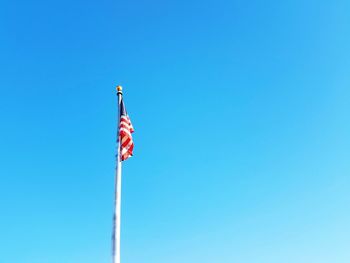 Low angle view of flag against clear blue sky