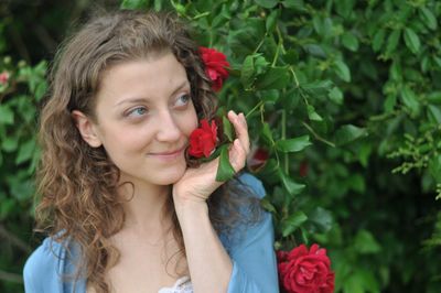 Portrait of smiling young woman holding red rose