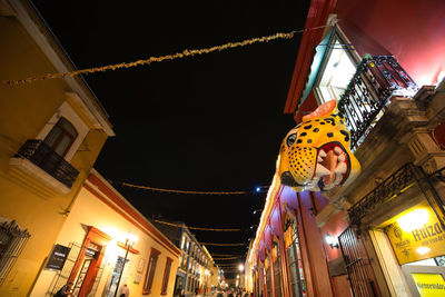 Low angle view of illuminated lanterns hanging amidst buildings in city at night