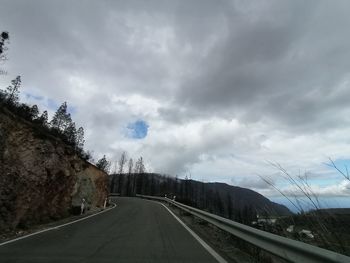 Road by trees against sky