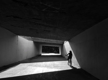 Rear view of woman cycling through underpass