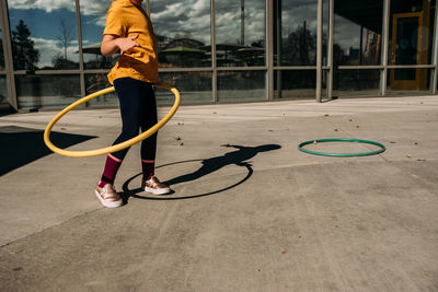 Young girl trying to hula hoop on a patio on a sunny day