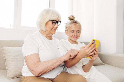 Young woman using mobile phone while sitting on sofa at home