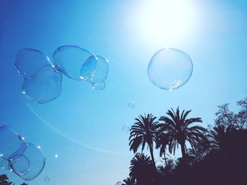 Low angle view of bubbles against blue sky