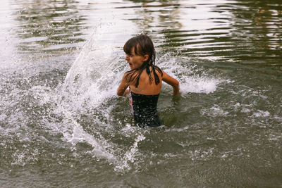 Full length of boy splashing water in sea