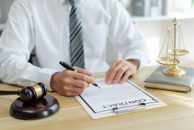 Midsection of lawyer working at desk in office