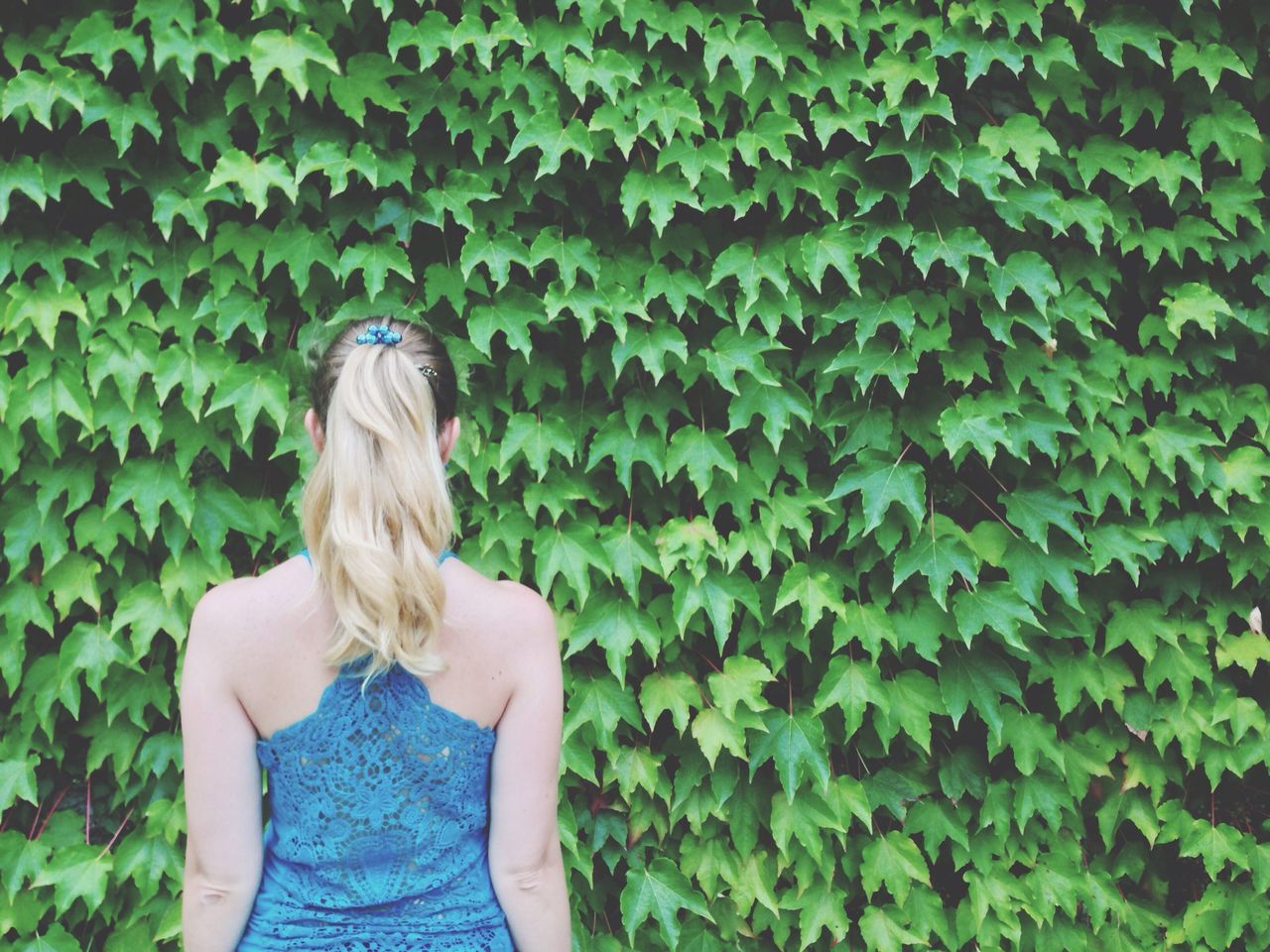 Rear view of woman standing in front of ivy