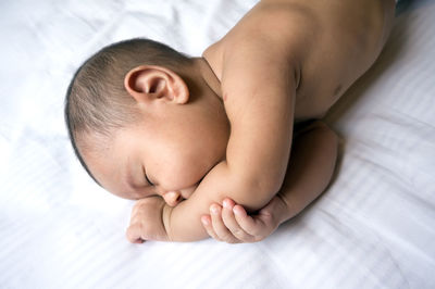 Close-up of baby lying on bed at home