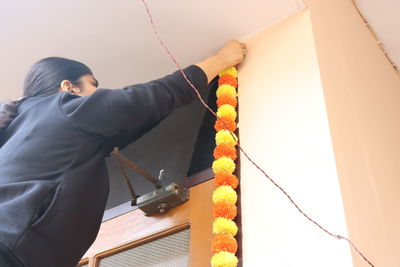 Midsection of woman holding rope hanging against wall