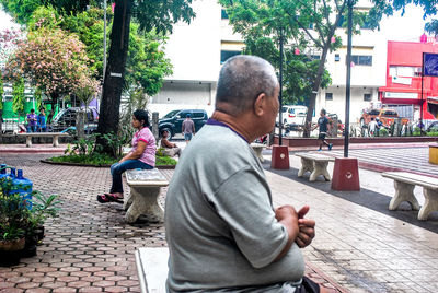 Man using mobile phone while sitting on tree