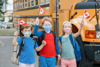 Proud happy students children with face masks holding canadian flags. education and back to school 