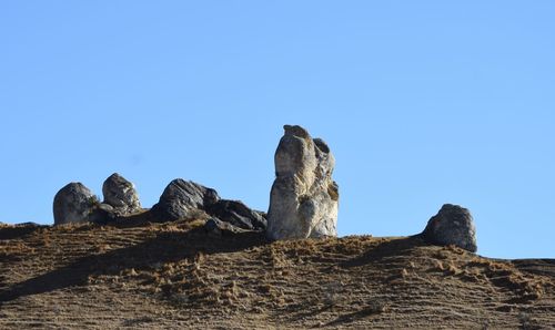 Low angle view of rock formation against clear blue sky