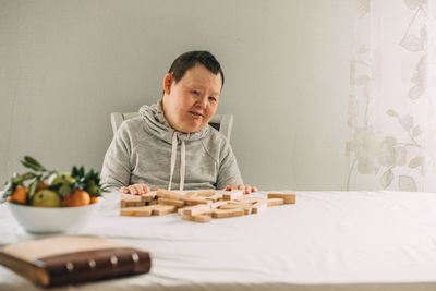 An elderly woman with down syndrome builds towers of their wooden toy blocks