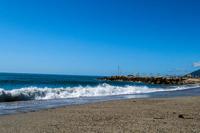 Scenic view of beach against clear blue sky