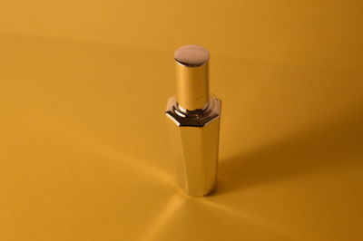 High angle view of yellow bottle against orange background