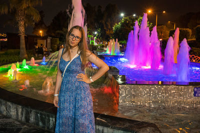 Portrait of smiling young woman standing by fountain