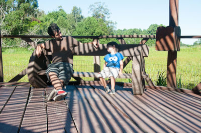 Full length of father and daughter sitting on grass