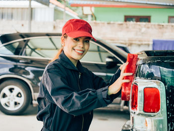 Portrait of female mechanic washing car