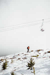 Man skiing on snowcapped mountain against clear sky