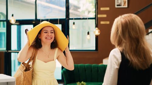 Portrait of young woman looking away while standing in cafe