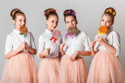 Portrait of girls having colorful lollipops against white background